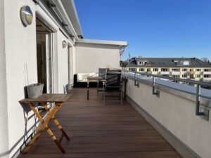 Grosszügige Dachterrasse mit Holzdielen und Balkonmöbeln in möblierter Wohnung in München West