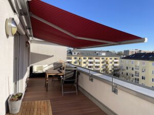 Rote elektrische Markise auf einer Dachterrasse in einer möblierten Wohnung in München Laim